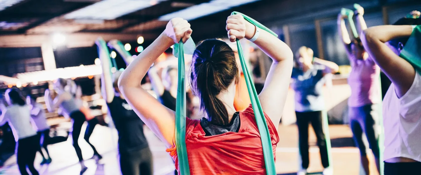 Woman stretching resistance bands over her head while working out at the YMCA